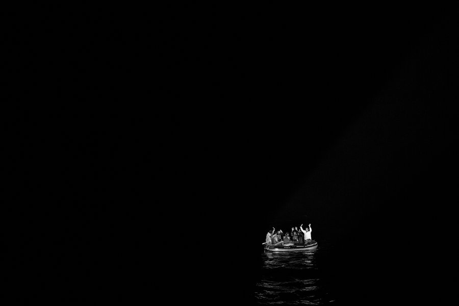 Turkey, Bodrum. 2015. A boat full of migrants is illuminated by the flashlights of Turkish coast guards who have come to rescue them near the Greek-Turkish border. This small boat's engine failed and 7 refugees from Syria, ‎Pakistan and Afghanistan were stucked in the middle of the sea. Then they called the coast guards to ask for help.