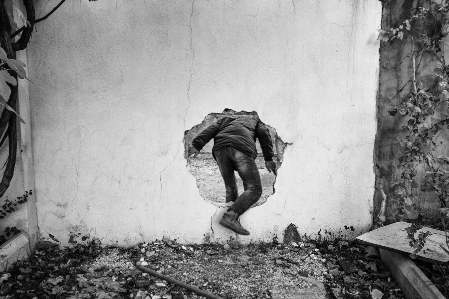 A member of Civilian Protection Unit (YPS) uses a wall’s hole to cross a street controlled by Turkish special military forces in Nusaybin, Turkey, December 2015.
